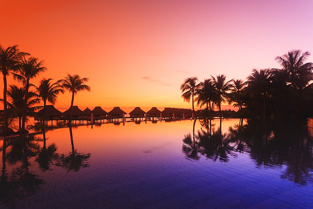 Sunset and palm trees reflecting in a pool at the bora bora nui resort and spa, Bora bora island society islands french polynesia south pacific