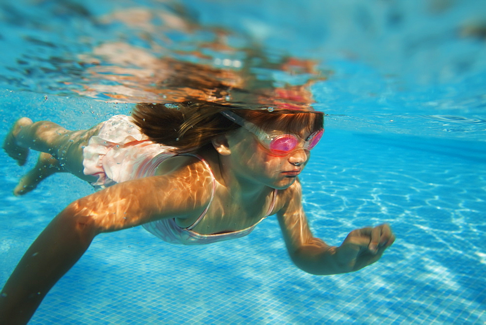 A girl swimming under the water in a pool with goggles on, Tarifa cadiz andalusia spain