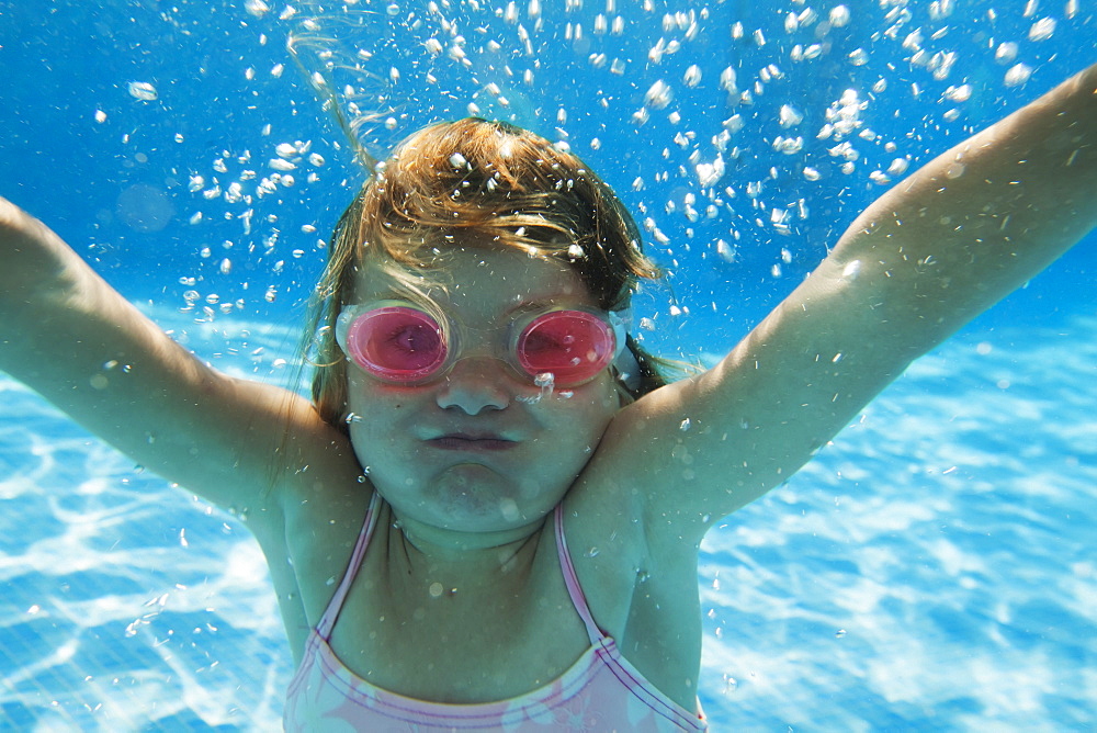 A girl swimming under the water in a pool with goggles on, Tarifa cadiz andalusia spain