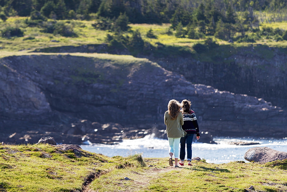 A Mother And Daughter Stand On A Trail Overlooking The Atlantic Coastline At Cape Spear, St. John's, Newfoundland And Labrador, Canada