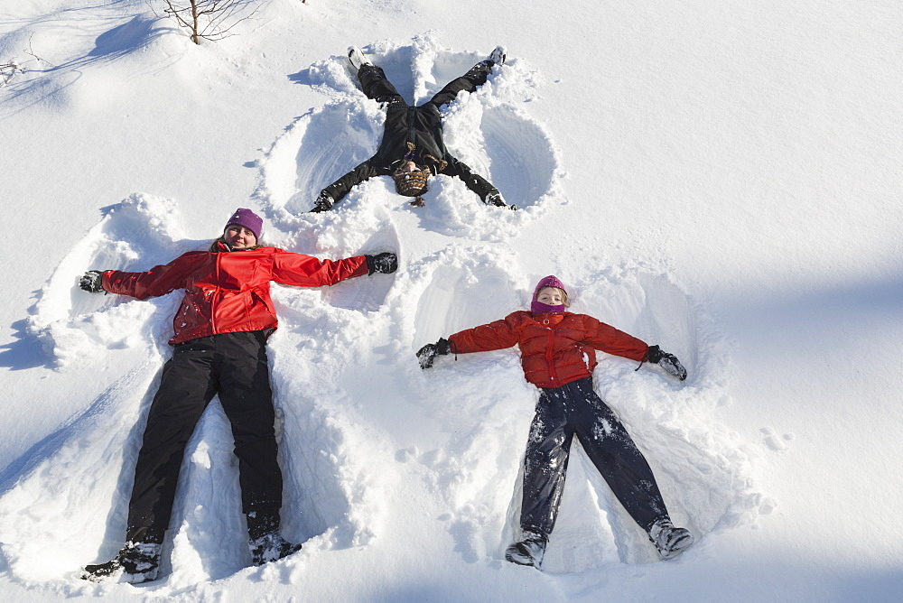 A Family Making Snow Angels In Wintertime, Talkeetna, Alaska, United States Of America