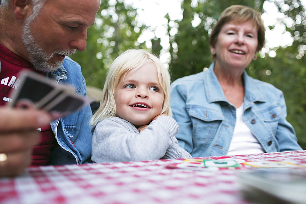 Grandparents Playing A Card Game With A Young Granddaughter, Peachland, British Columbia, Canada