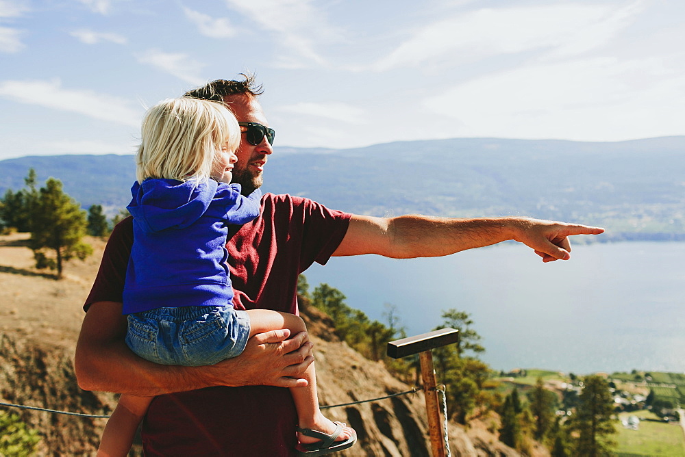 A Father Holds His Young Daughter As They Look Out Over Lake Okanagan, Peachland, British Columbia, Canada