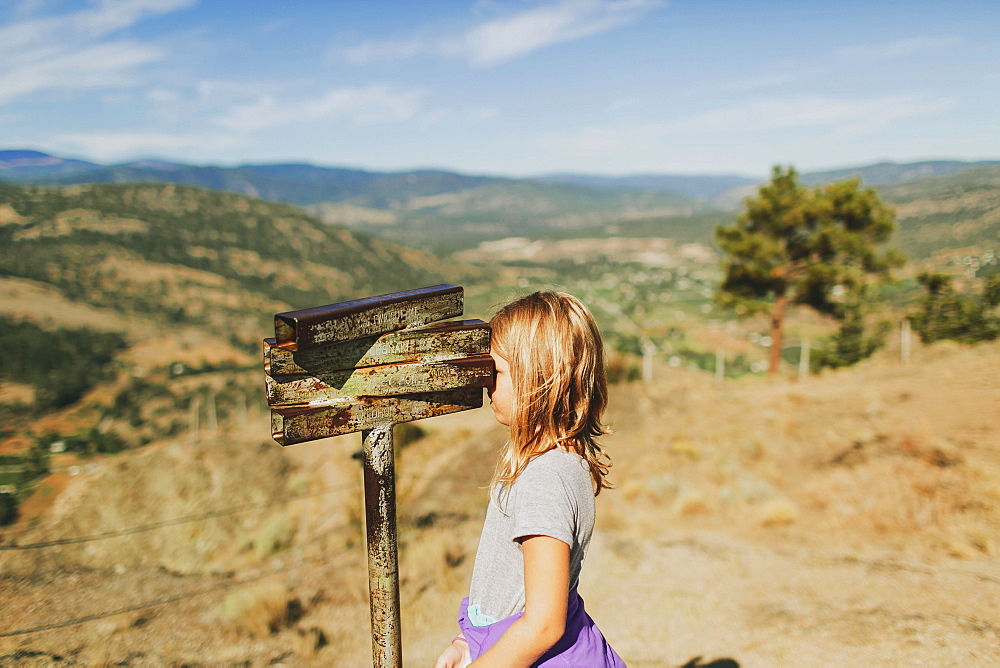 A Young Girl Looks Through An Old Rusty Set Of Binoculars, Peachland, British Columbia, Canada