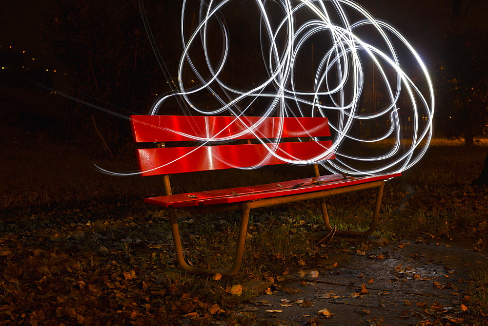 A Red Park Bench In Autumn With Swirls Of White Light In The Sky Around It, Locarno, Ticino, Switzerland