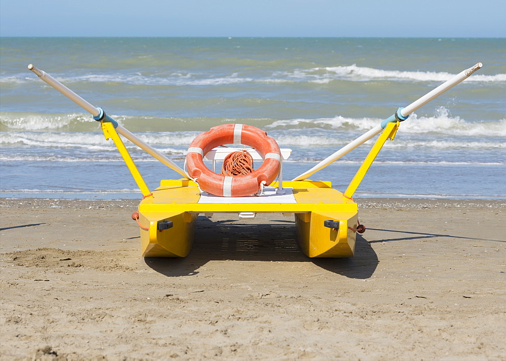 A Lifeboat Sitting On The Beach At The Water's Edge, Rimini, Emilia-Romagna, Italy