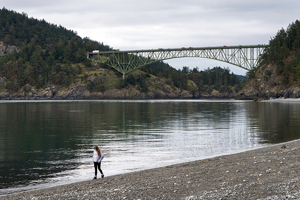 A Young Woman Walks On A Rocky Beach In Deception Pass State Park, Oak Harbor, Washington, United States Of America