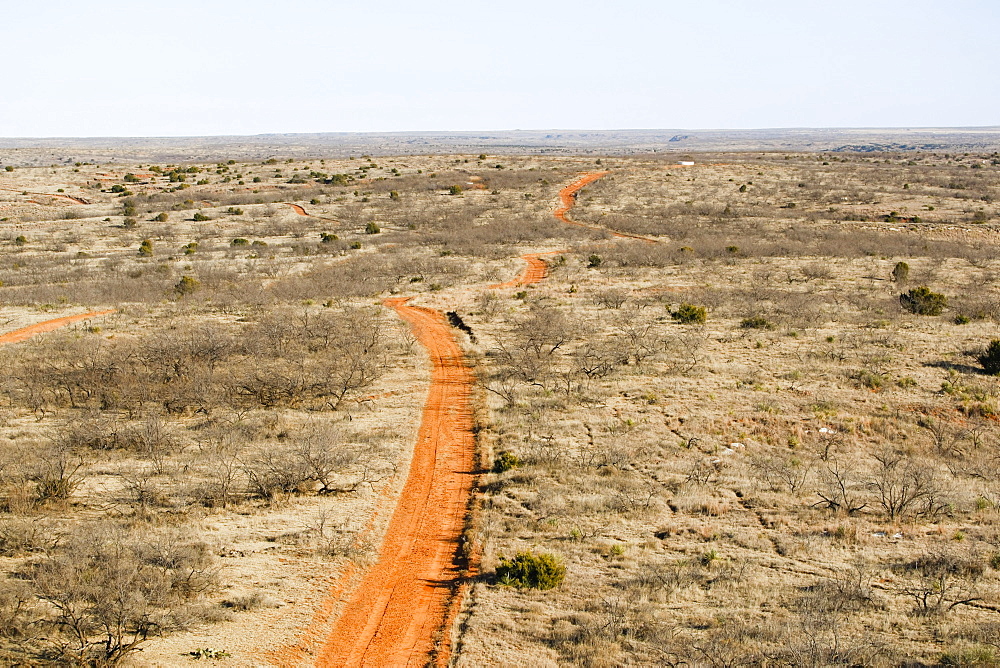 Agriculture - Aerial view of a dirt road passing through West Texas rangelands, sparse land used for cattle grazing / near Northfield, Texas, USA.