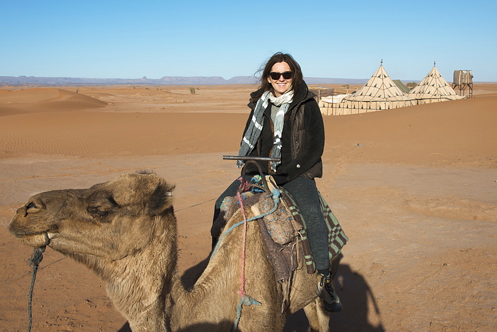 A woman riding a camel on the erg chegaga dunes, Souss-massa-draa morocco