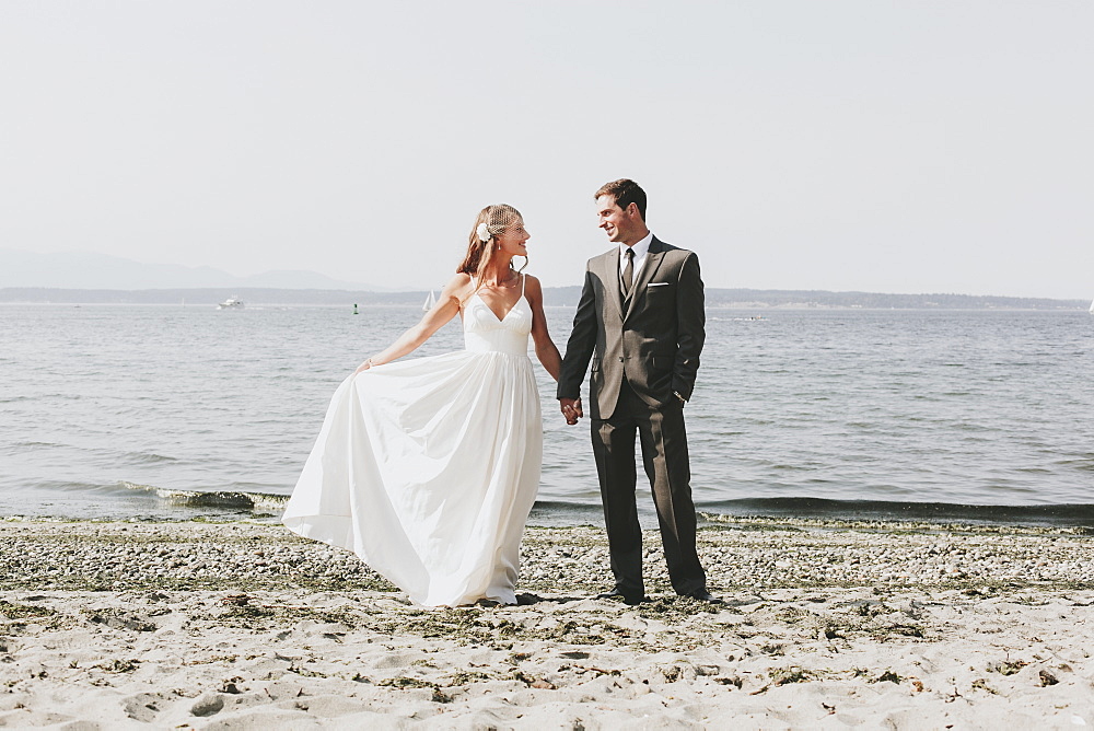 A bride and groom on a beach at the water's edge, Kirkland washington united states of america