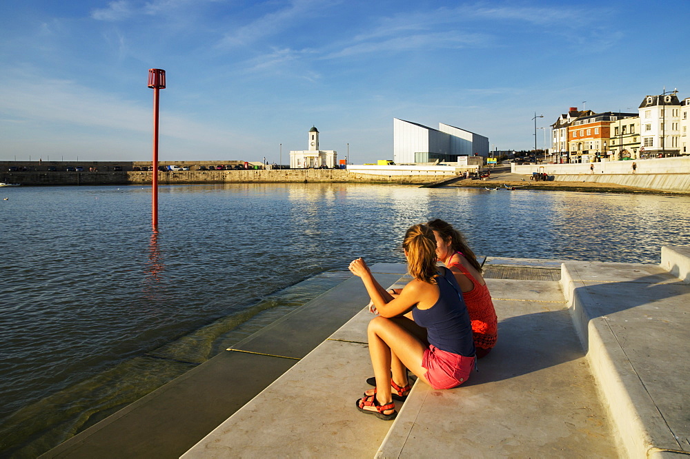 Teenage Girls Sitting On Steps Along The Waterfront, Margate, Kent, England