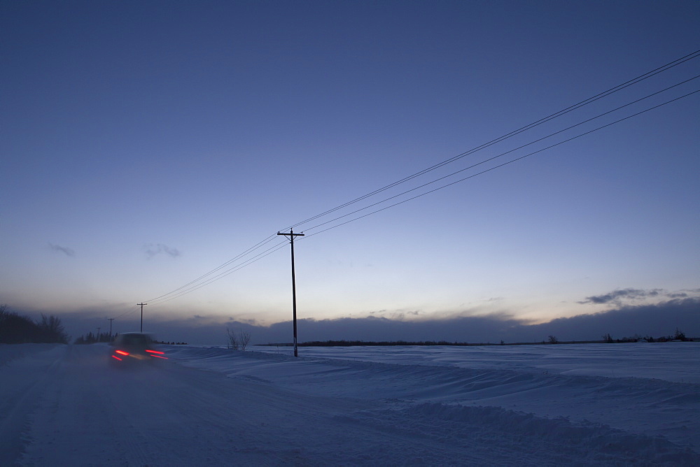 Car Travelling Along Old School Road At Dusk In Winter, Caledon, Ontario, Canada