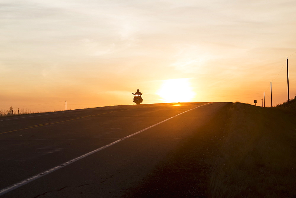 Man On A Motorcycle At Twilight On A Highway, Near Edmonton, Alberta, Canada