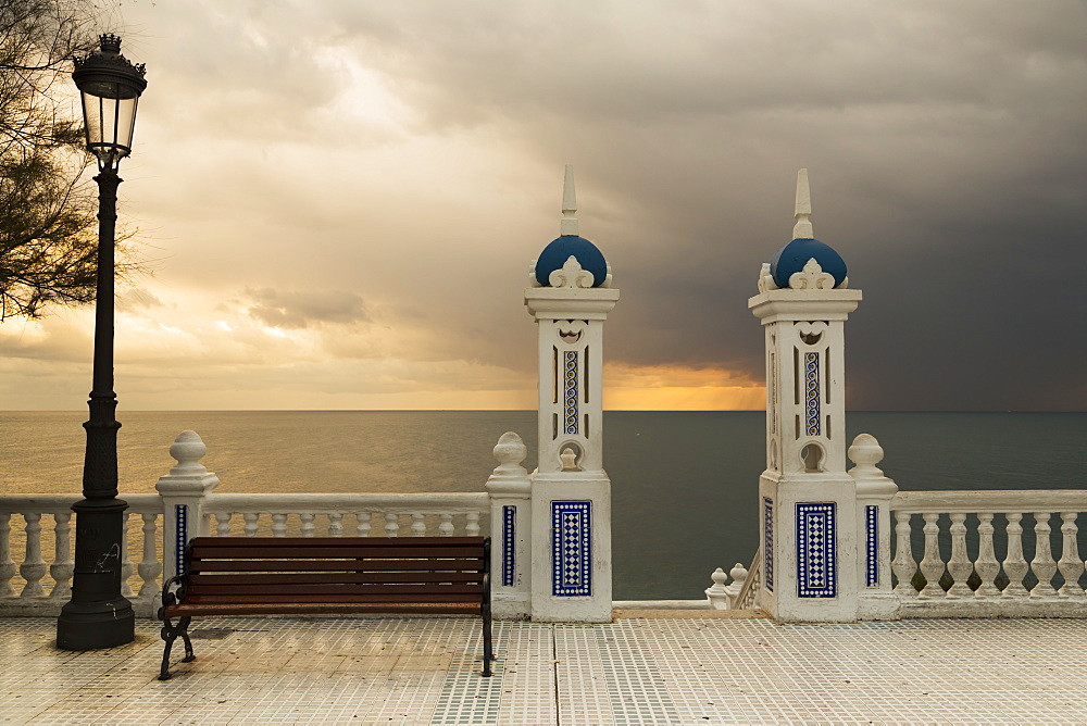 Decorative Railing And Pillars On The Promenade With A Bench And Lamppost At Sunset, Benidorm, Spain