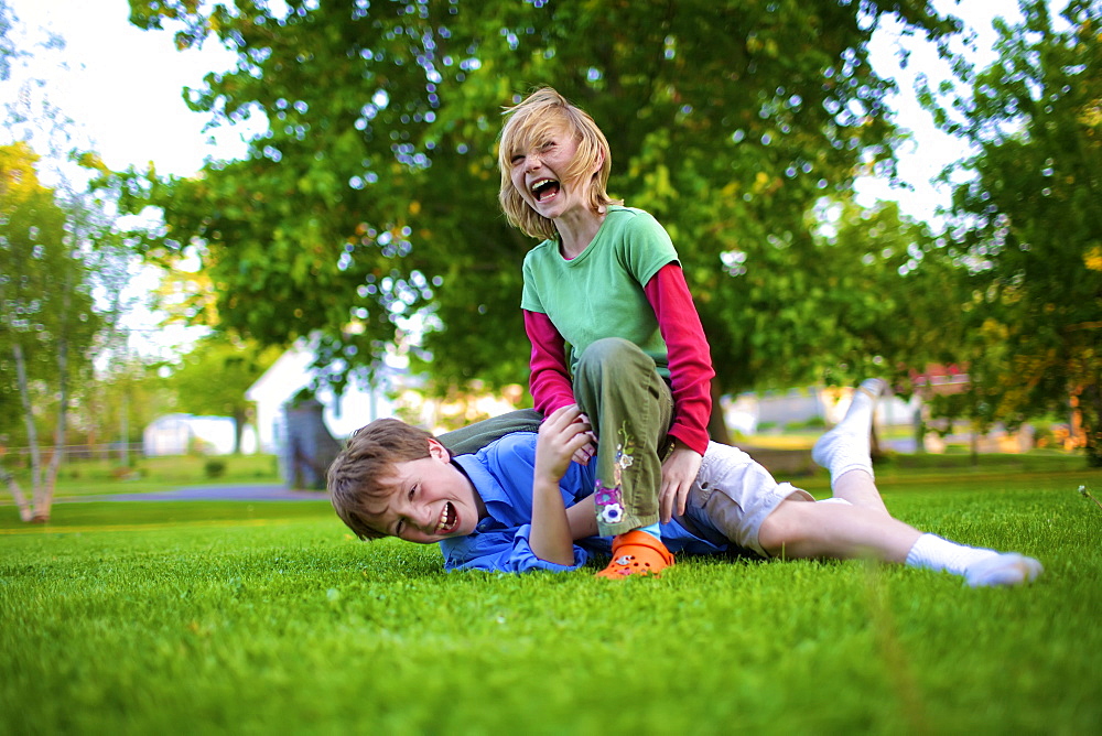 A Boy And Girl Wrestling On The Grass, Picton, Ontario, Canada