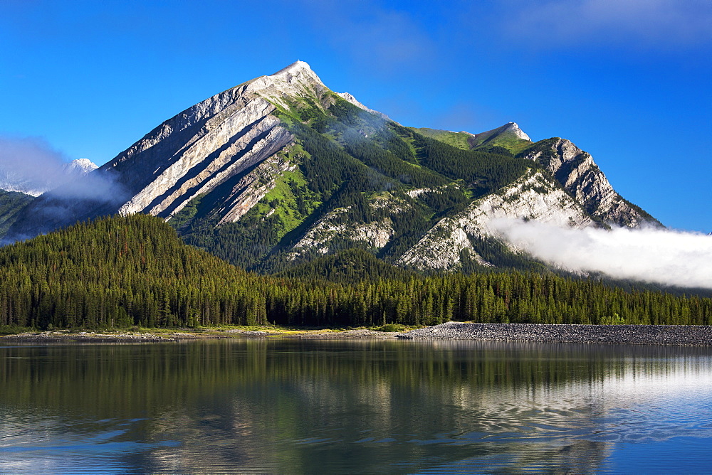 Mountain Reflecting In Lake With Fog Patches And Blue Sky, Kananaskis Country, Alberta, Canada