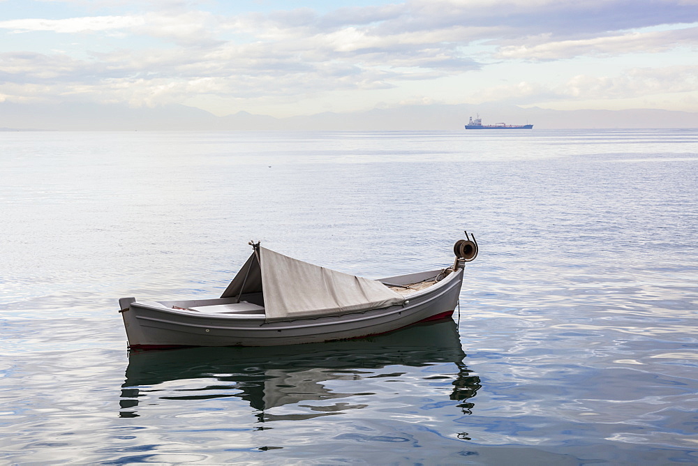 A Boat Floating On The Tranquil Aegean Sea With A Ship In The Distance, Thessaloniki, Greece