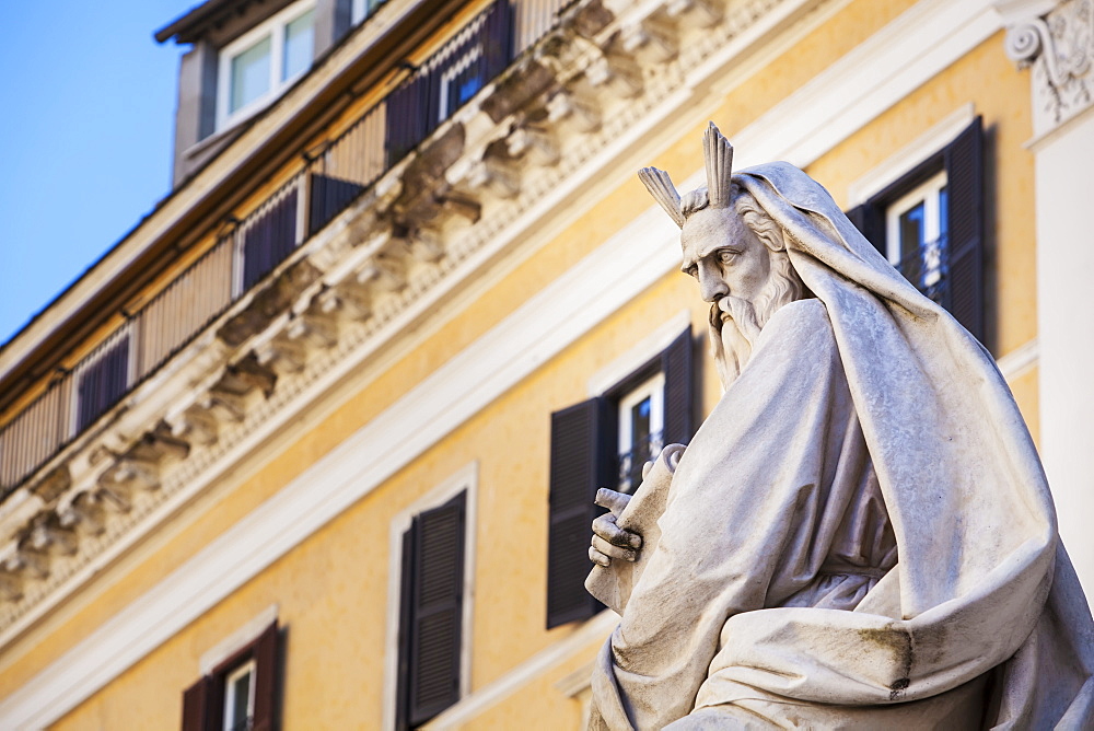 Statue Of Historical Male Figure And Yellow Building, Rome, Italy