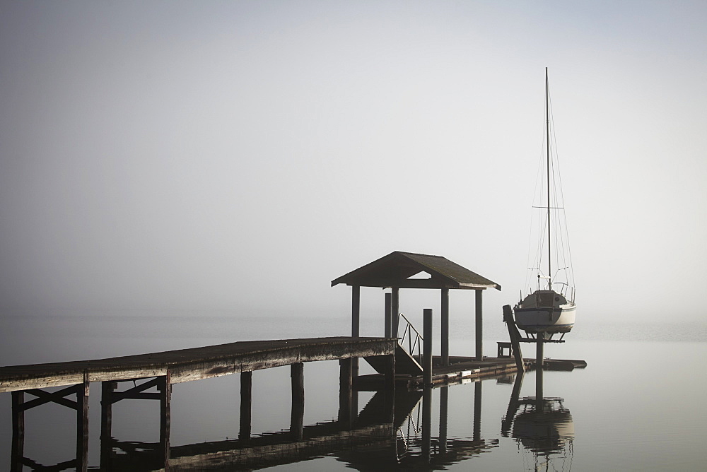 Sailboat On Lift By Dock On Foggy Lake, Bellingham, Washington, United States Of America