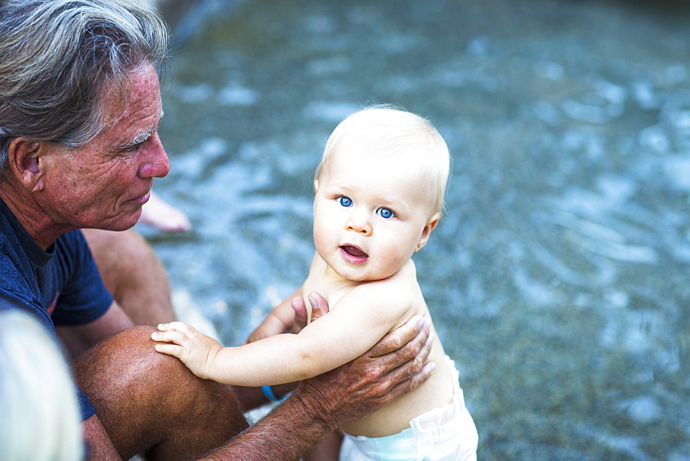 A Grandfather Holds A Young Baby At The Poolside, Fountain Valley, California, United States Of America