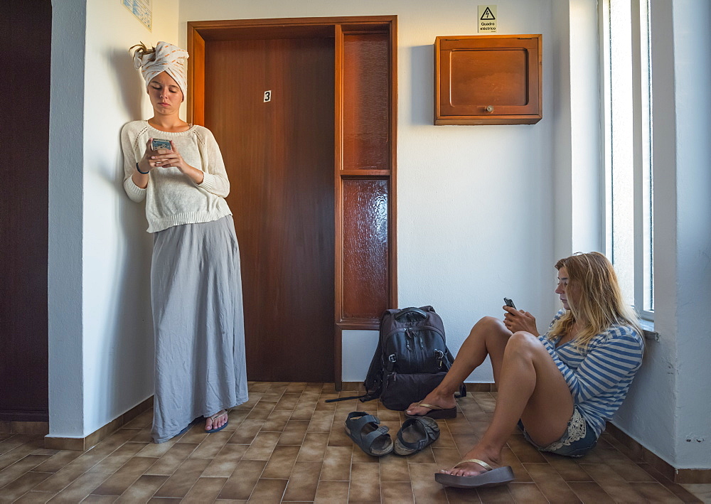 Two Young Women In Their Apartment Using Their Smart Phones, Sagres, Portugal