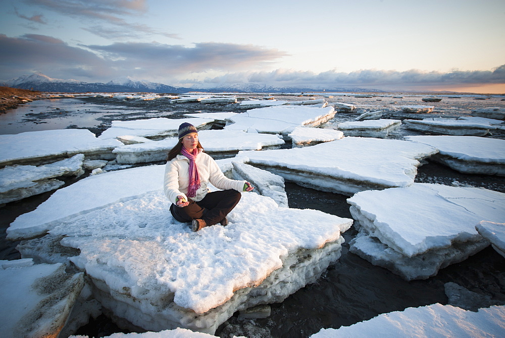 Woman Practicing Meditation On Ice Chunks Stacked Against The Homer Spit, Southcentral Alaska