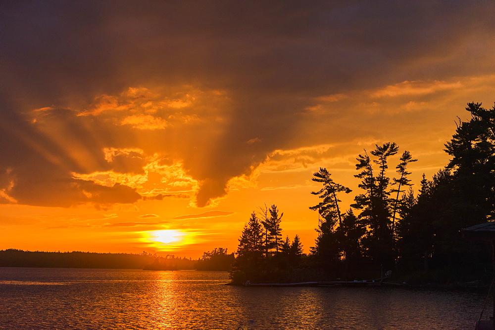 Sunrise Casting An Orange Glow Over The Sky And Reflected In A Tranquil Lake, Ontario, Canada