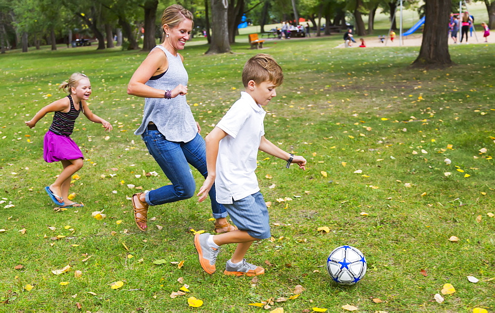 A Mother Playing Soccer With Her Kids In A Park During A Family Outing, Edmonton, Alberta, Canada