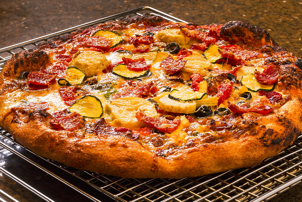 Close Up Of A Golden Crust Oven Baked Pizza On A Cooling Rack With Roasted Zucchini, Peppers, Artichokes, Mushrooms, Olives, Calgary, Alberta, Canada