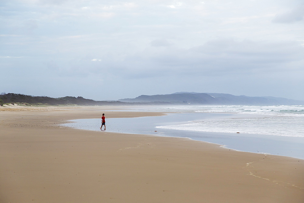 Person Walks Towards The Water On A Beach Along The Noose North Shore Under A Cloudy Sky, Noosa, Queensland, Australia