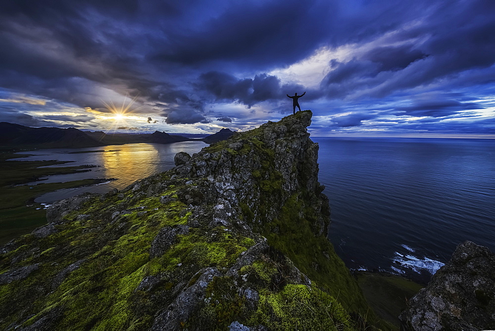 Man Standing On Top Of A Sea Cliff At Sunset Along Iceland's Strandir Coast In The West Fjord Region, Iceland