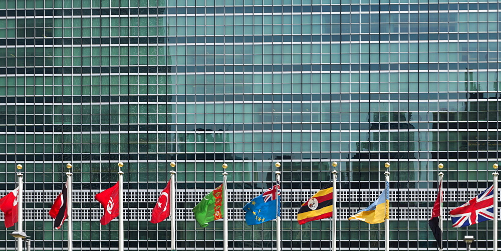 International Flags In A Row In Front Of A Headquarters Of The United Nations Building With Glass Facade, New York City, New York, United States Of America