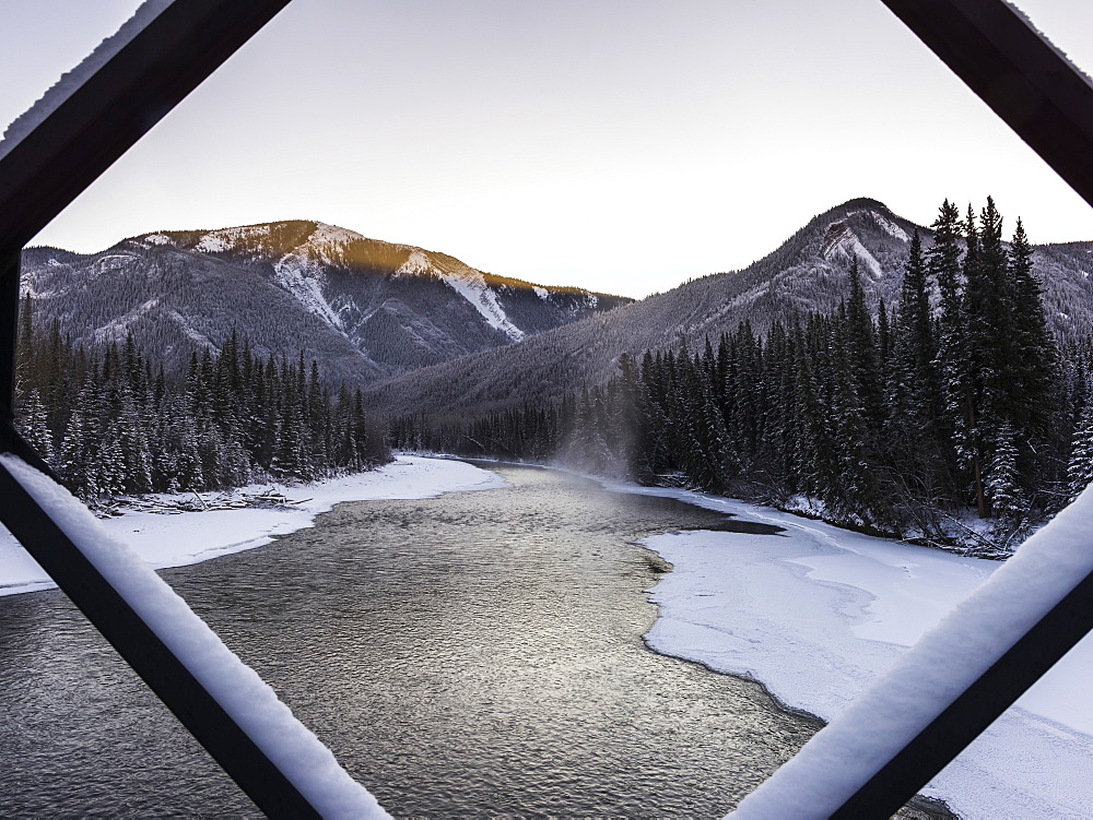 A Landscape With Snow Along The Shoreline Of A Lake And A Mountain Range Viewed Through A Diamond Shaped Window Frame, British Columbia, Canada