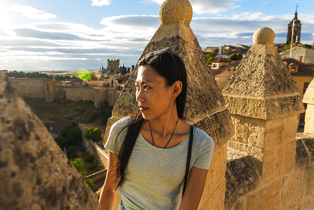 Asian Girl Sitting On The Ancient Walls Of Segovia, Segovia, Castilla Leon, Spain