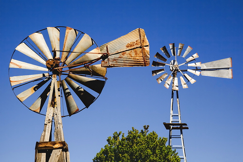 Close Up View Of Two Old Windmills Standing In The Yard Of A Farm, Quemado, New Mexico, United States Of America