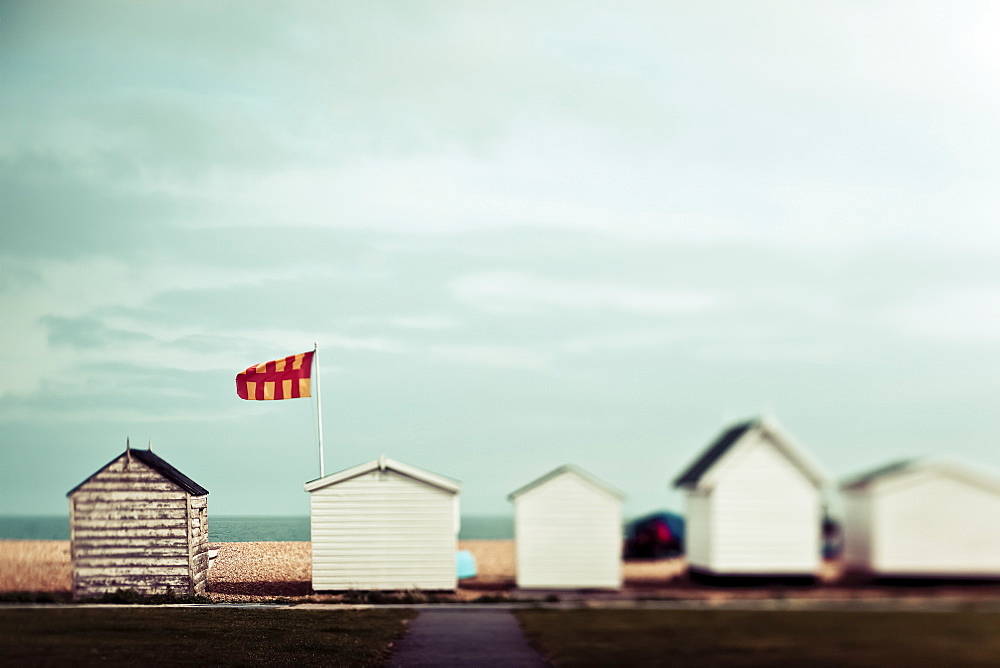 Small wooden buildings in a row on the beach with a view of the ocean, England