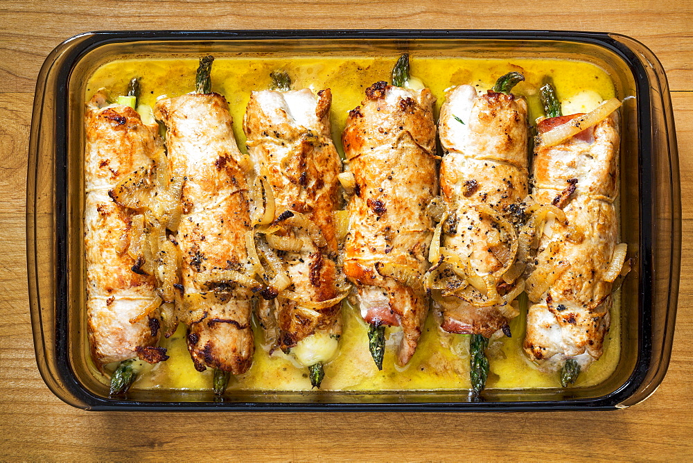 Glass Casserole Dish On Wooden Cutting Board Filled With Rolled Browned Chicken Stuffed With Asparagus In A Cream Sauce, Calgary, Alberta, Canada