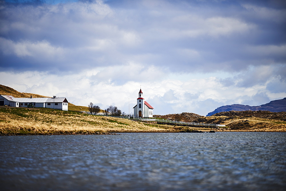 Church With A Red Roof, Barn And Farmhouse Along A Lake, Iceland