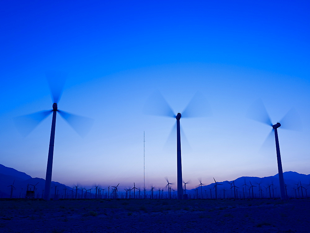 Silhouette Of Wind Turbines In A Field With A Mountain Range In The Distance At Sunset, Palm Springs, California, United States Of America