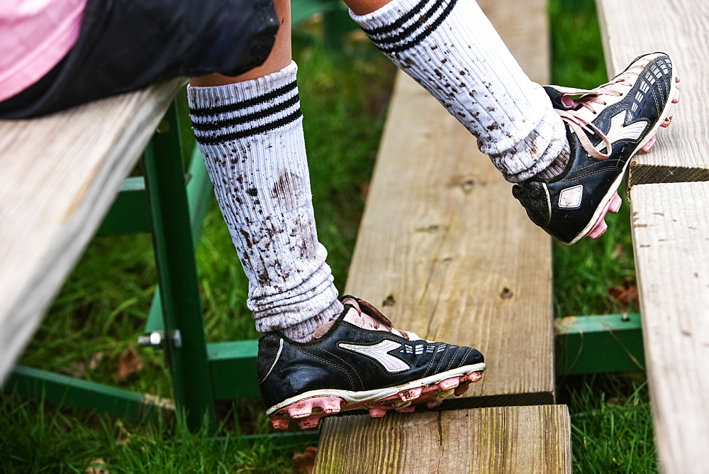 A Soccer Player Sitting On Wooden Stands Wearing Cleats And Mud Splashed Socks, Oregon, United States Of America