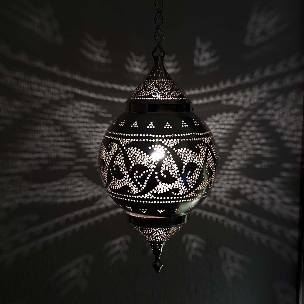 Illuminated hanging light fixture reflecting pattern on the wall, Istanbul turkey