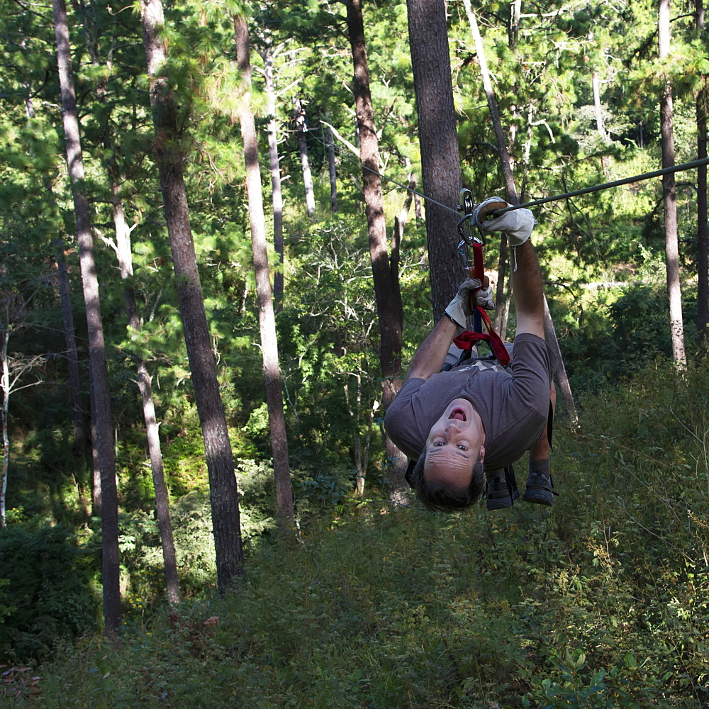 A Man Hangs Upside Down On A Zip-Line, Copan, Honduras