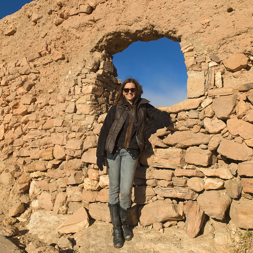 A woman posing by a rock wall with a window, Ait benhaddou sous-massa-draa morocco