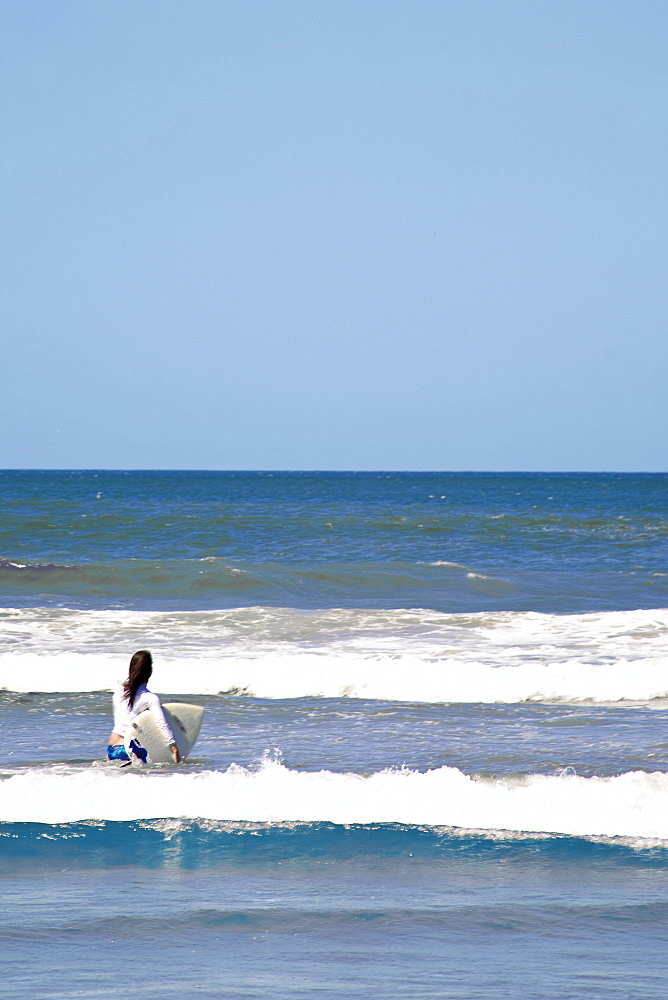 Woman Taking Surfboard Into Sea