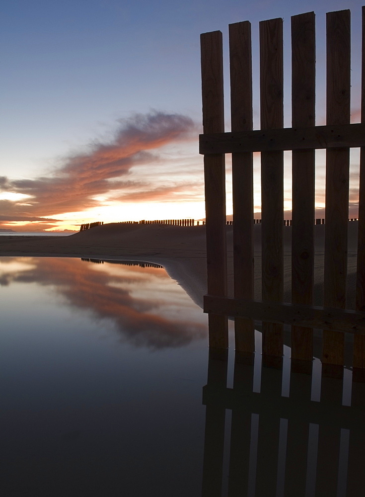 Wooden Fence Along Shoreline Of Beach