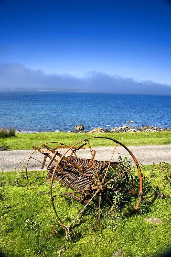 Old Farm Machinery Beside A Road And Lake