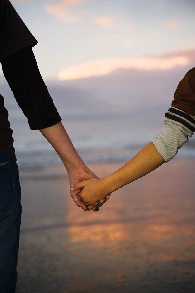 Two People Holding Hands On The Beach, Waihi Beach, New Zealand