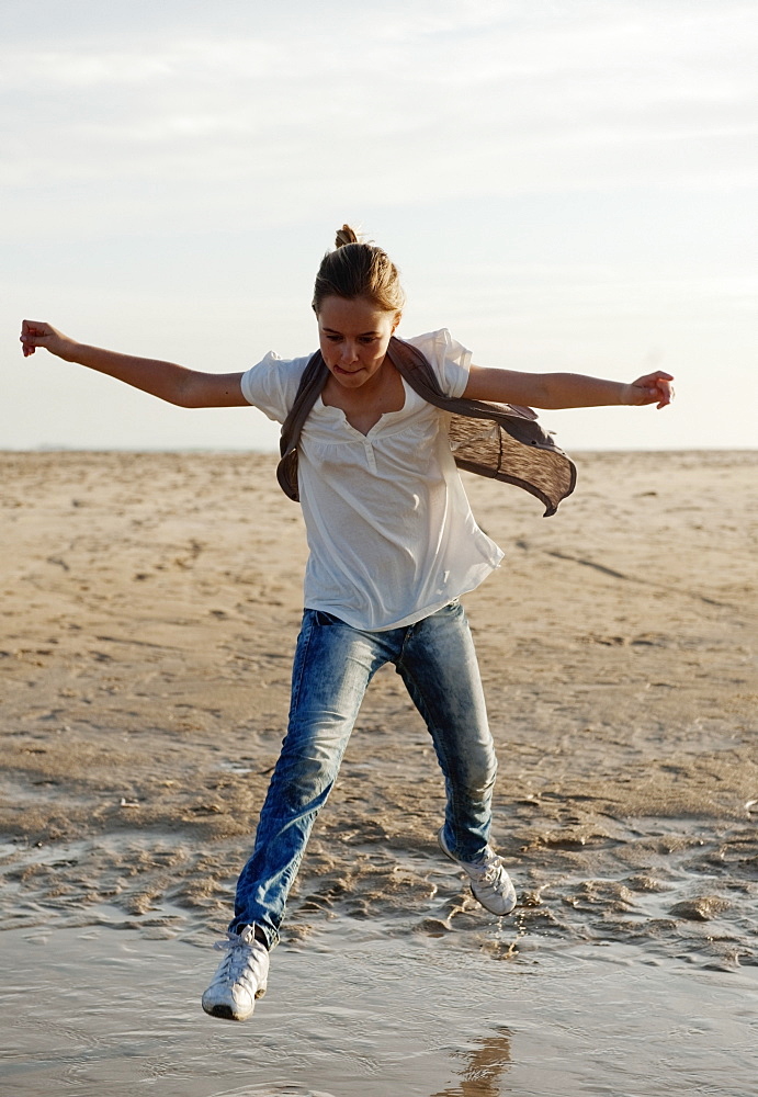 A Girl Jumps Over The Water On Los Lances Beach Along Costa De La Luz, Tarifa, Cadiz, Andalusia, Spain