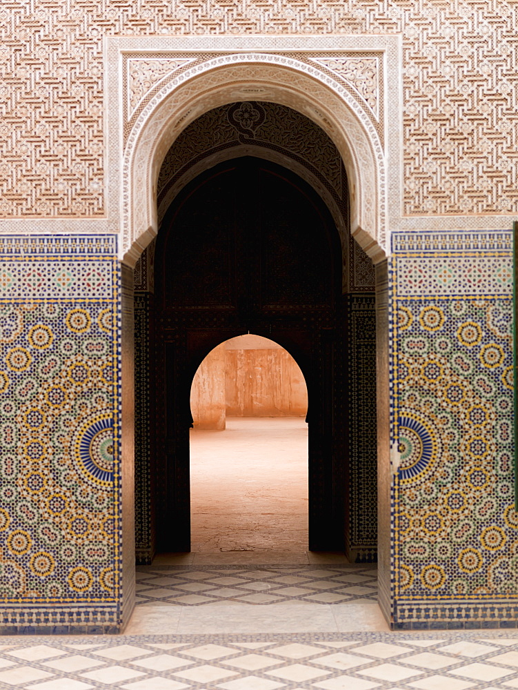 A doorway in a keyhole shape with a colourful tile design on the wall