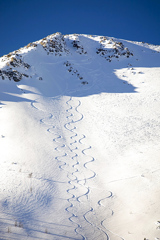 Snow covered mountain peak with skier tracks and deep blue sky, Lake louise alberta canada